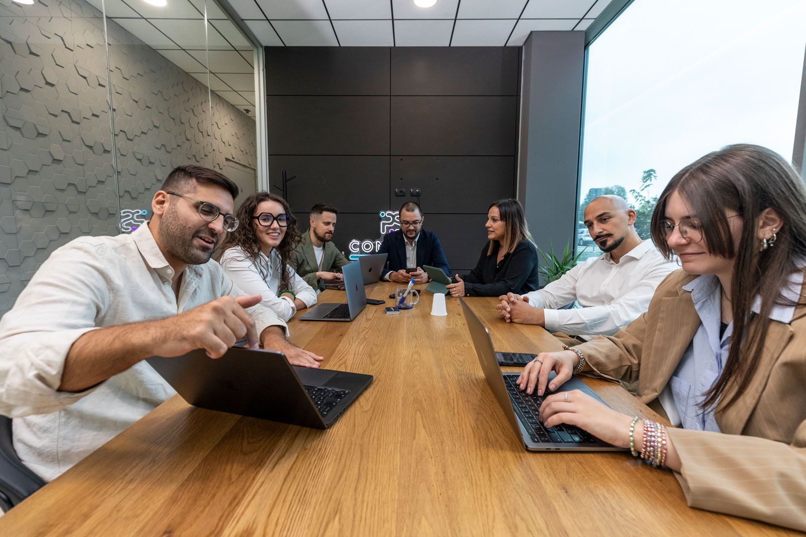 Un gruppo di persone è seduto a un tavolo con i propri computer portatili.