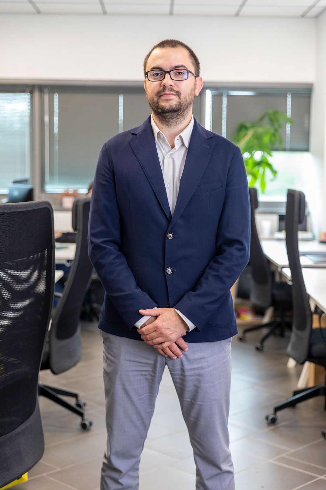Un uomo in giacca e occhiali è in piedi in un ufficio.