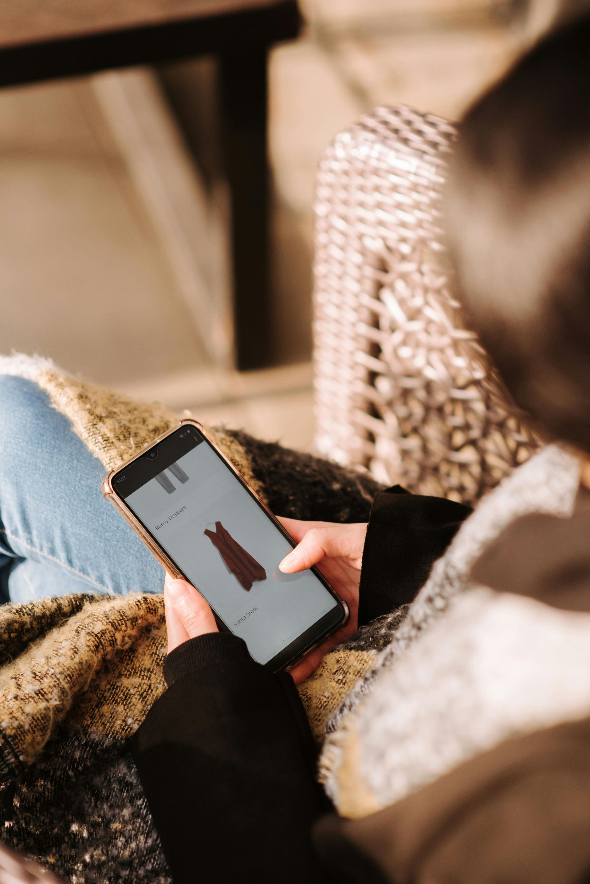 Una donna è seduta su un divano e tiene in mano un telefono cellulare.