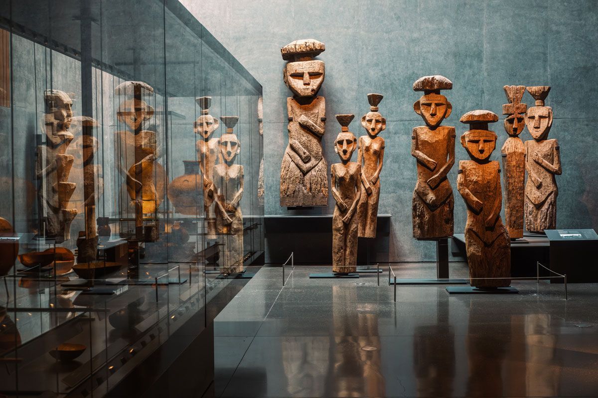 Un gruppo di statue di legno sono esposte in un museo.