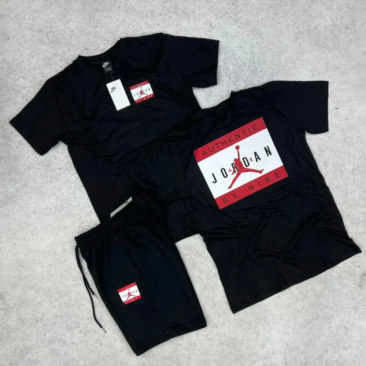 Conjunto de camiseta y shorts Jordan negros. Una camiseta tiene la etiqueta de Nike y las otras el logo de Jordan.
