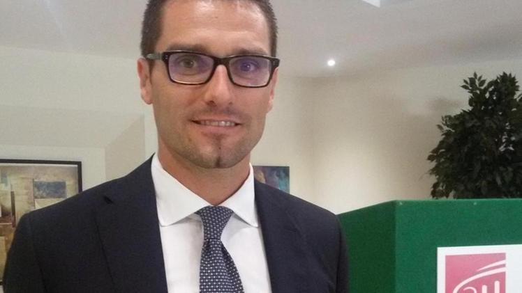 Un uomo in giacca e cravatta è in piedi accanto a una scatola verde.