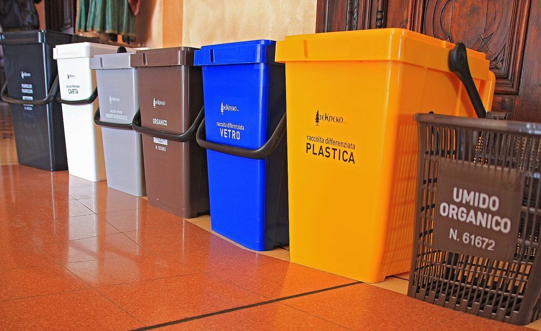 Una fila di contenitori per il riciclaggio tra cui uno con la scritta umido organico