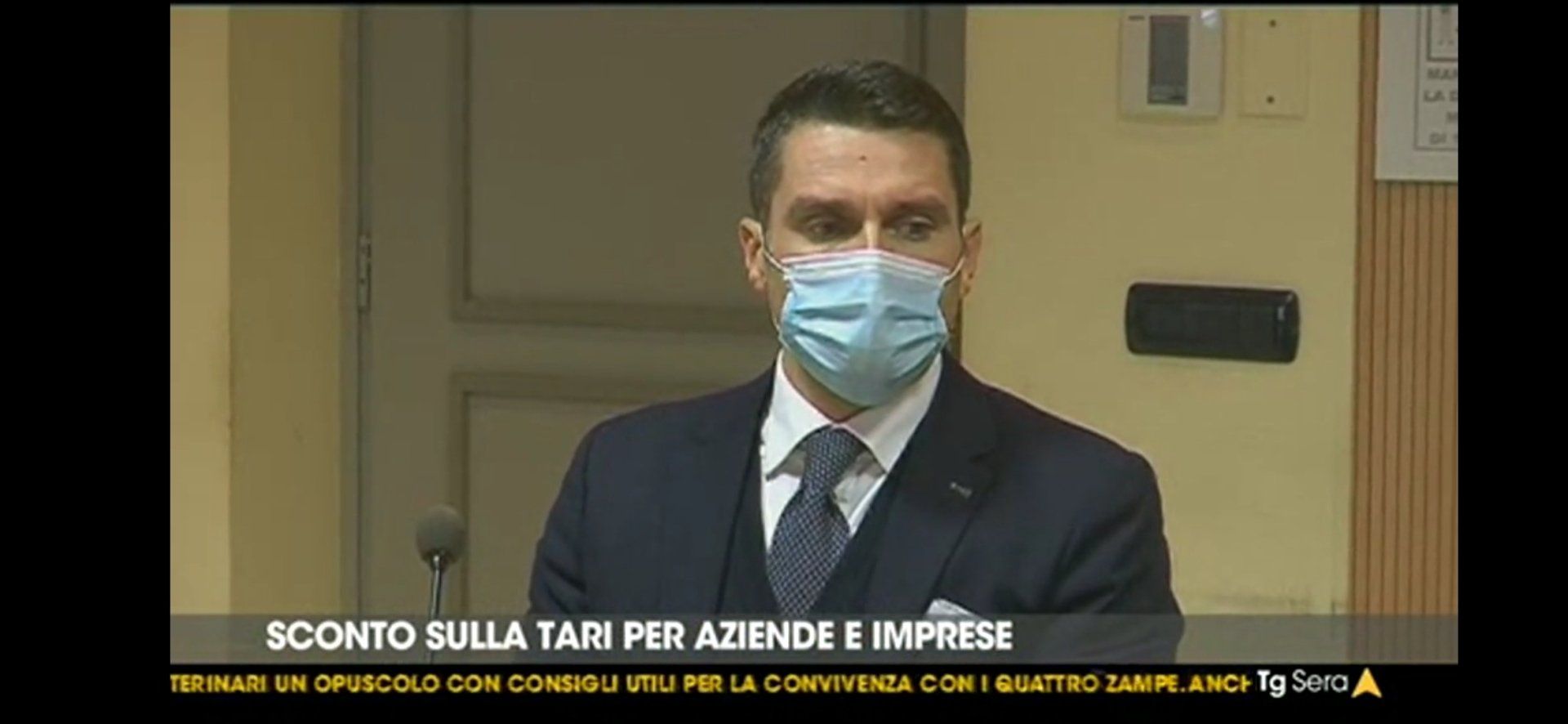 Un uomo in giacca e cravatta indossa una maschera