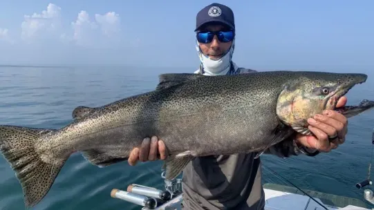 A man is holding a large fish in his hands on a boat.