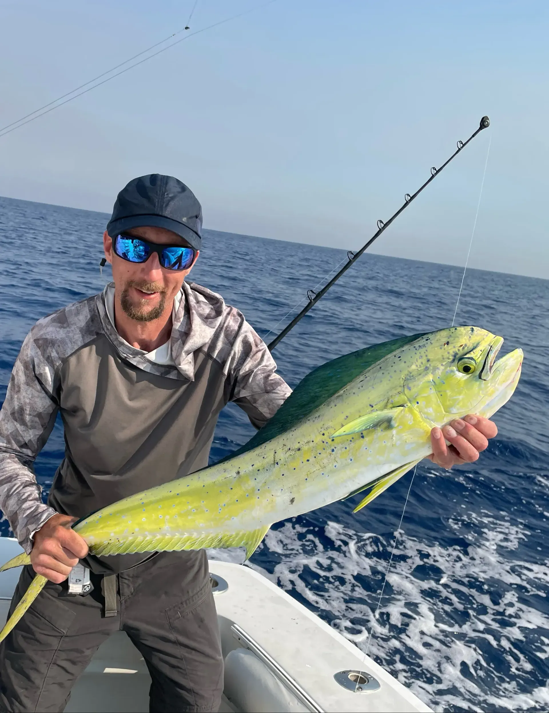 A man is holding a large fish on a boat in the ocean.