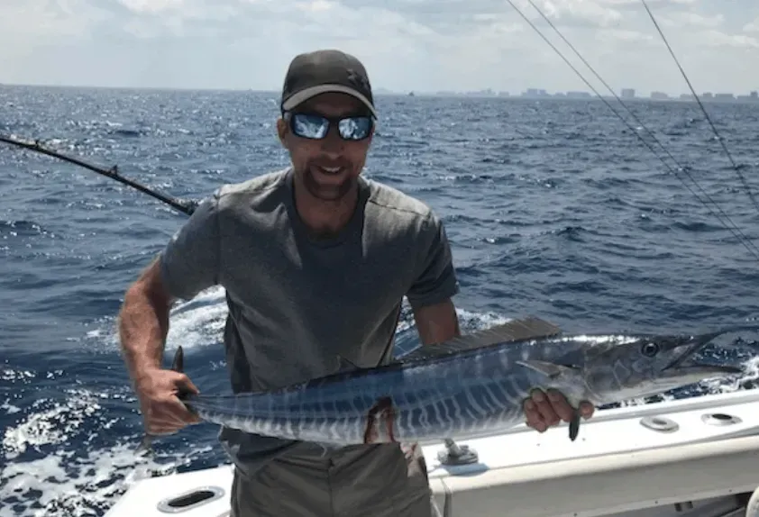 A man is holding a large fish on a boat in the ocean.