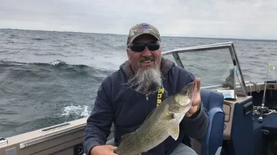 A man is sitting on a boat holding a large fish.