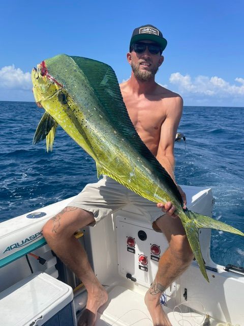 A man is sitting on a boat holding a large fish.