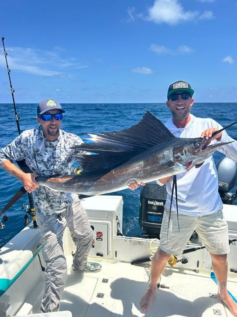Two men on a boat holding a large sailfish
