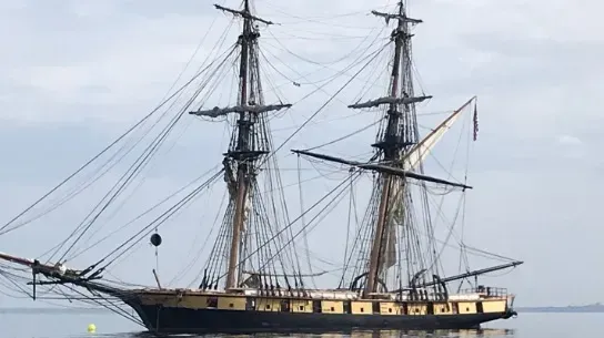 A large sailing ship is floating on top of a body of water.