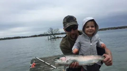 A man and a child are holding a fish in their hands.