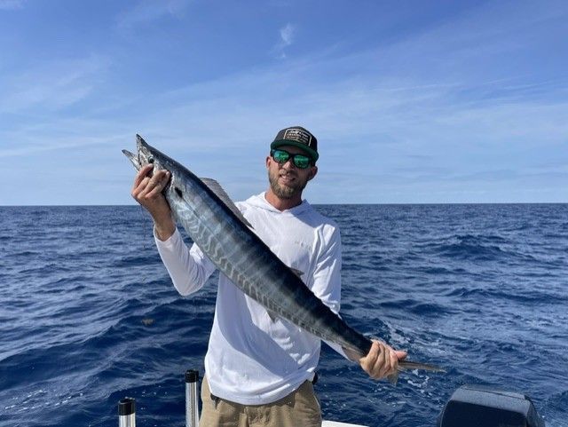 A man is holding a large fish on a boat in the ocean.