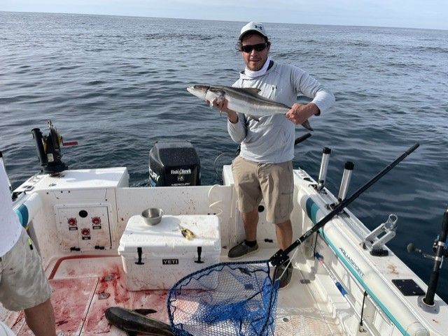 A man is standing on a boat holding a fish