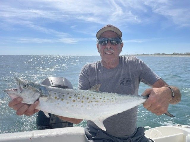 A man is holding a fish on a boat in the ocean.