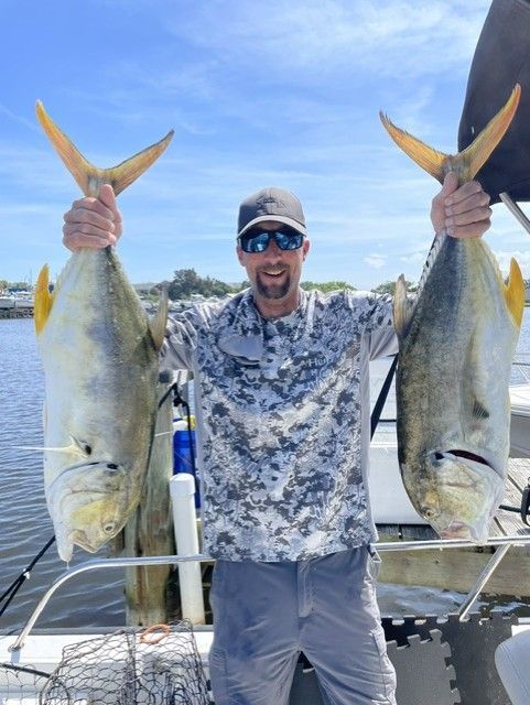 A man is holding two fish in his hands on a boat