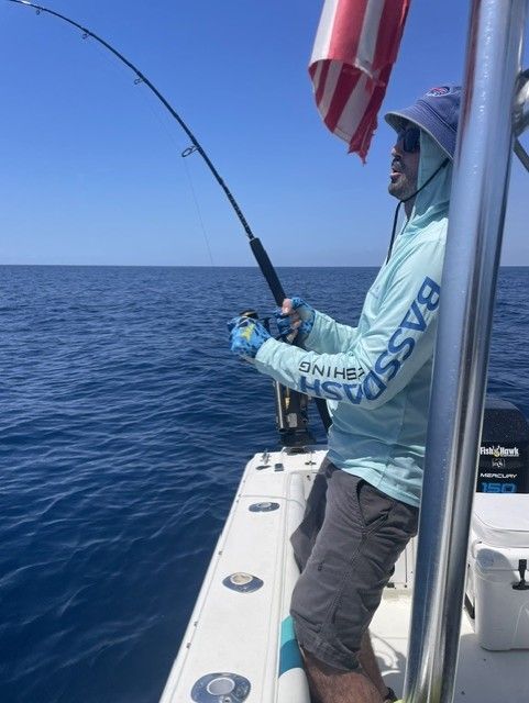 A man is fishing on a boat in the ocean.