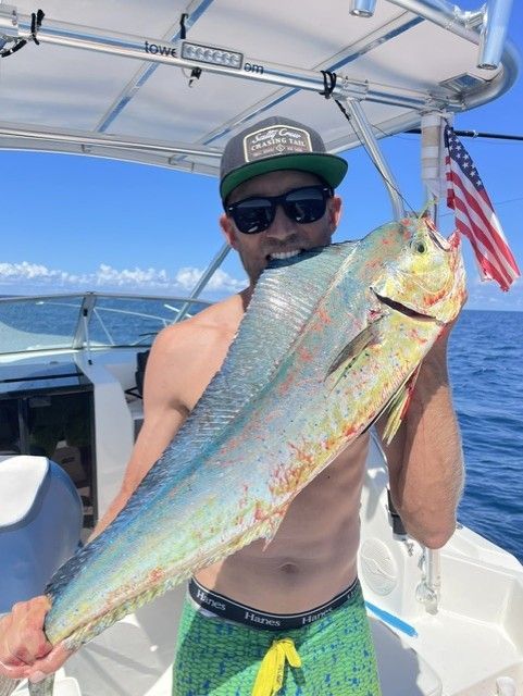 A man on a boat holding a large fish in his mouth