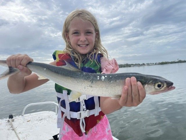 A little girl is holding a fish in her hands on a boat.