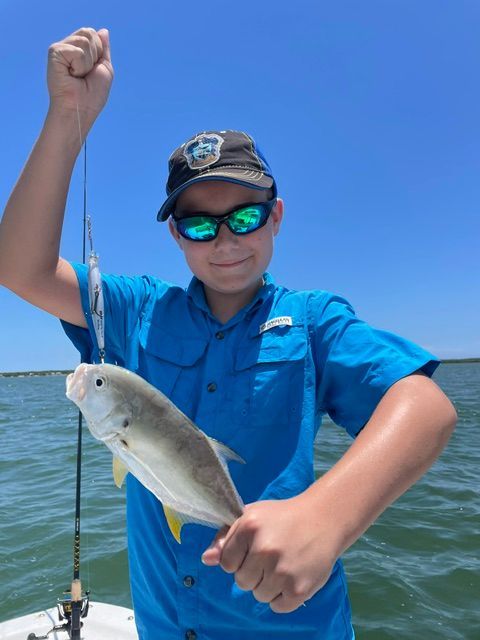 A boy in a blue shirt is holding a small fish