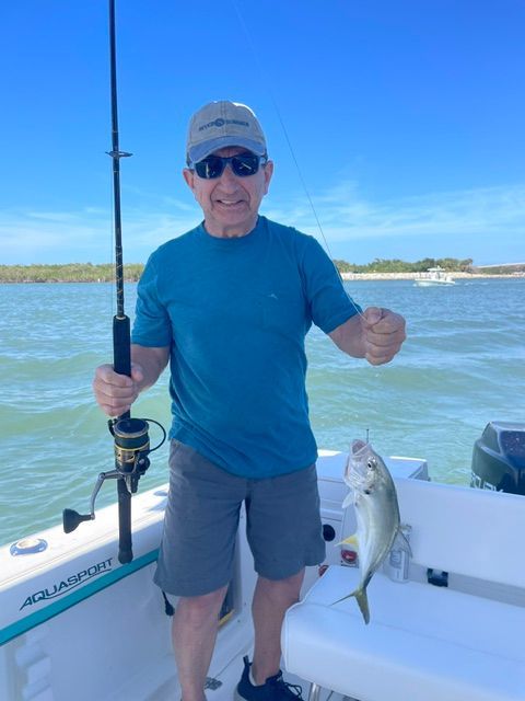 A man on a boat holding a fishing rod and a fish