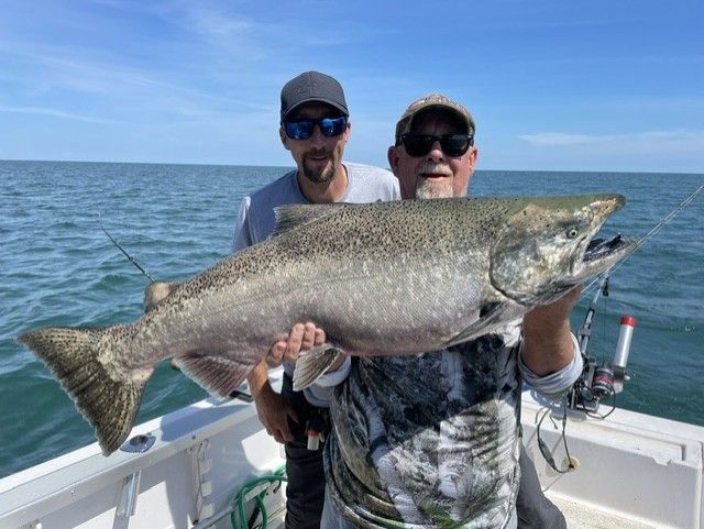 Two men are holding a large fish on a boat.