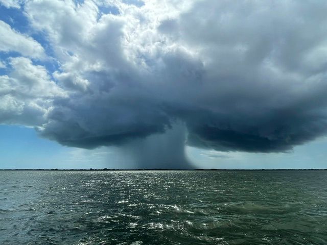 A large cloud is moving over a body of water.