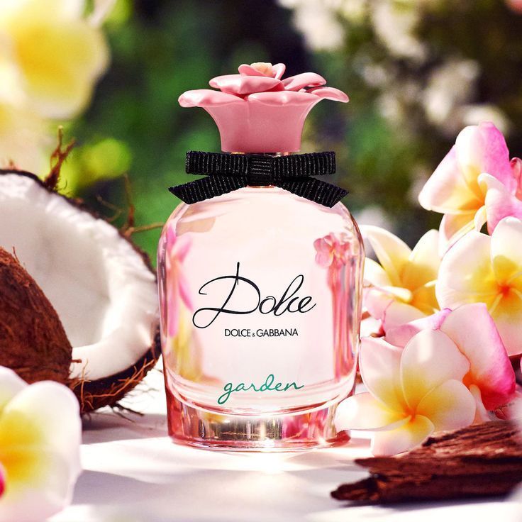 Una bottiglia di profumo Dolce e Gabbana è circondata da fiori e noci di cocco.