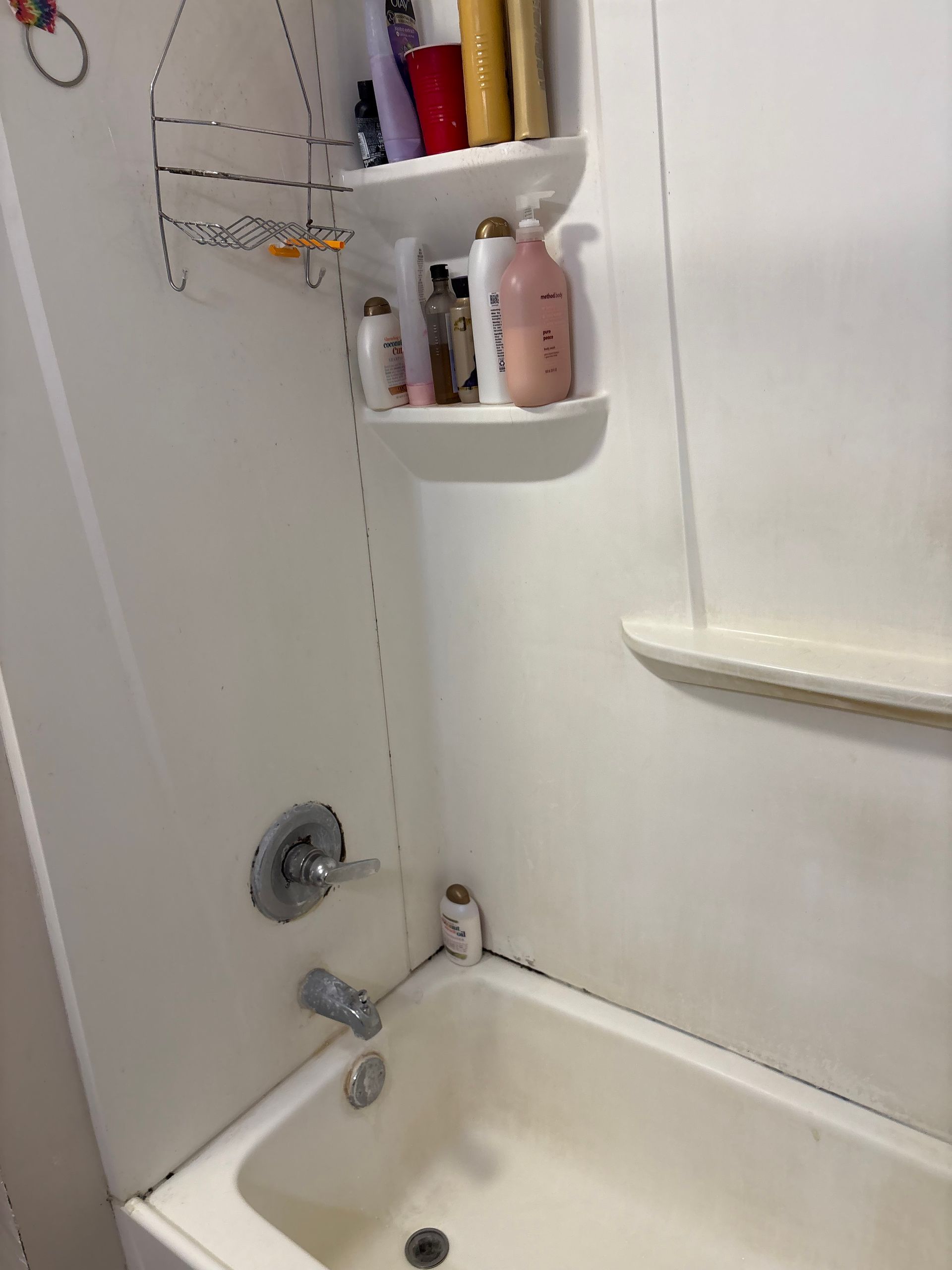 White bathtub with shower fixtures and shelves holding toiletries.
