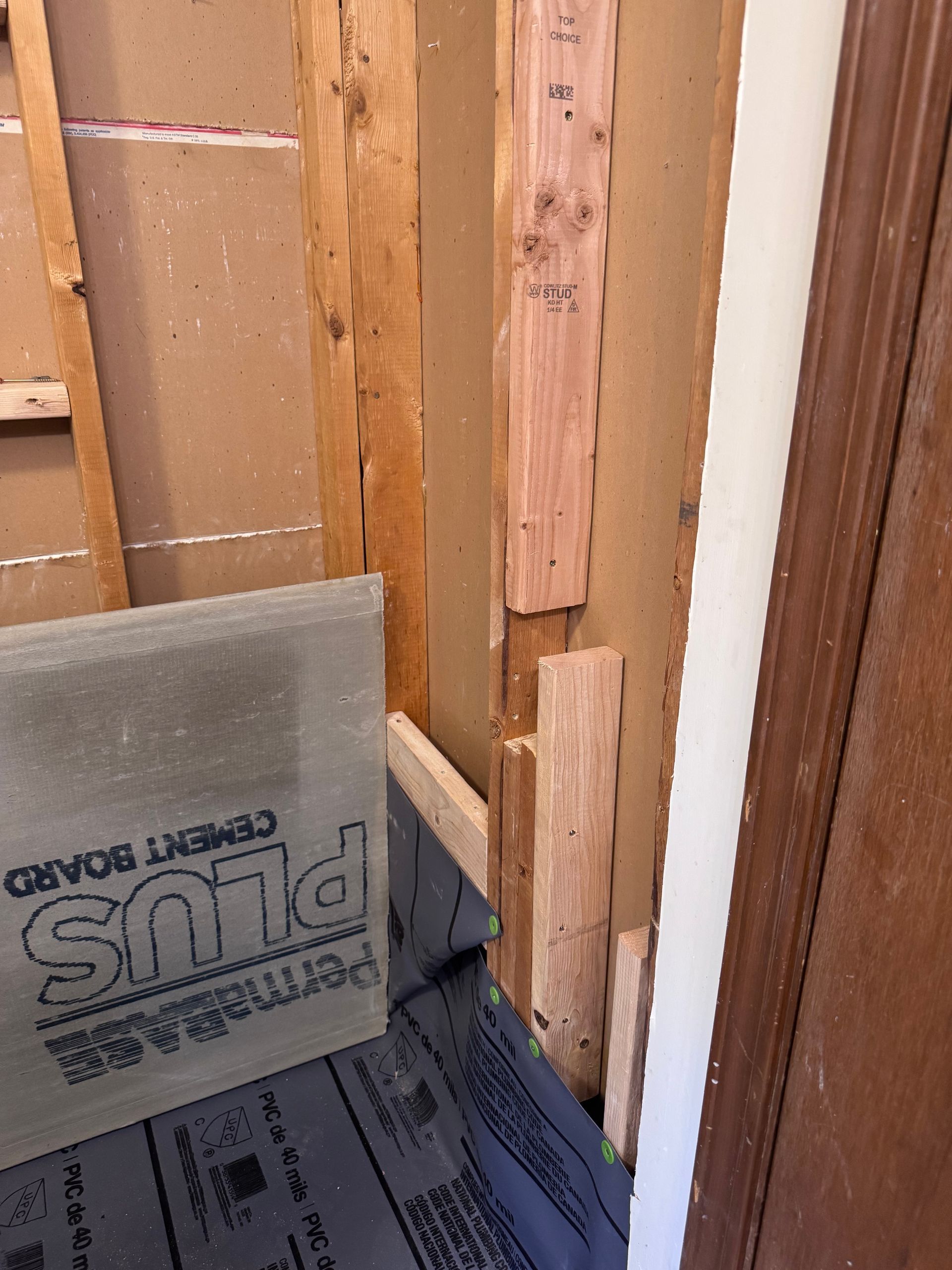 Construction site with cement board, wood framing, and waterproof membrane in a bathroom.