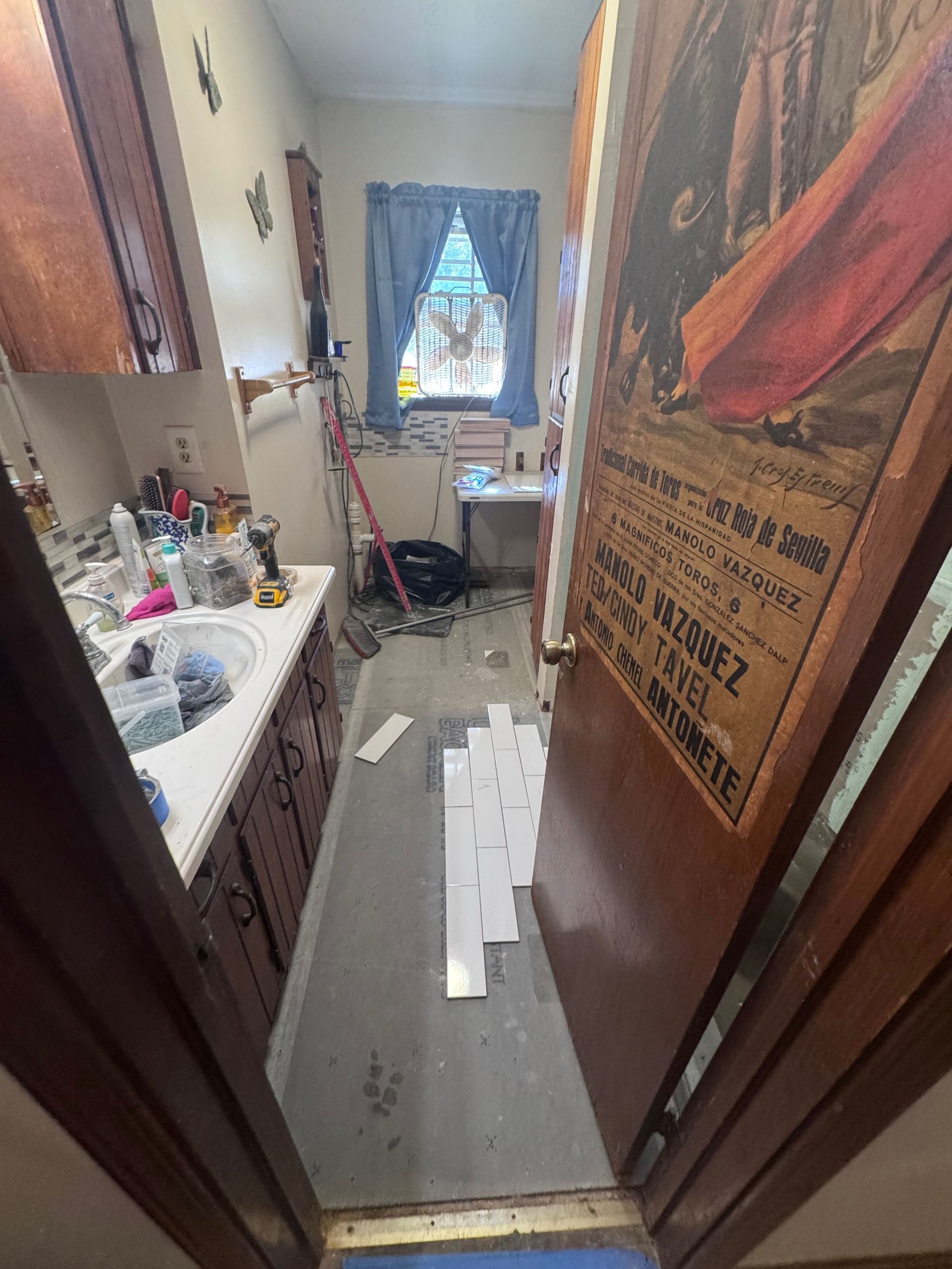 Narrow bathroom with tiling project in progress; sink and open doorway.