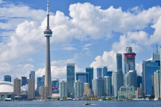 Toronto skyline with CN Tower, blue water, and sky with clouds.