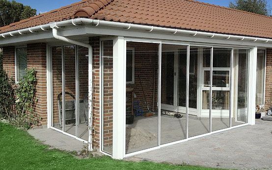 Et murstenshus med en afskærmet veranda, skydedøre og et rødt tegltag
