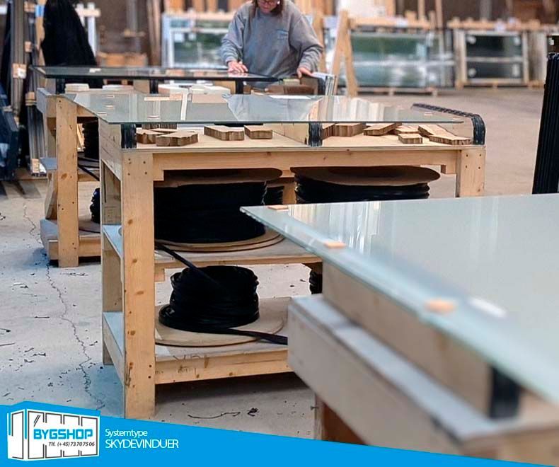 Foto af skydeglas der fremstilles i produktionen. Glas afpudses for silikonerester fra glassets produktion og skydevinduerne samles.