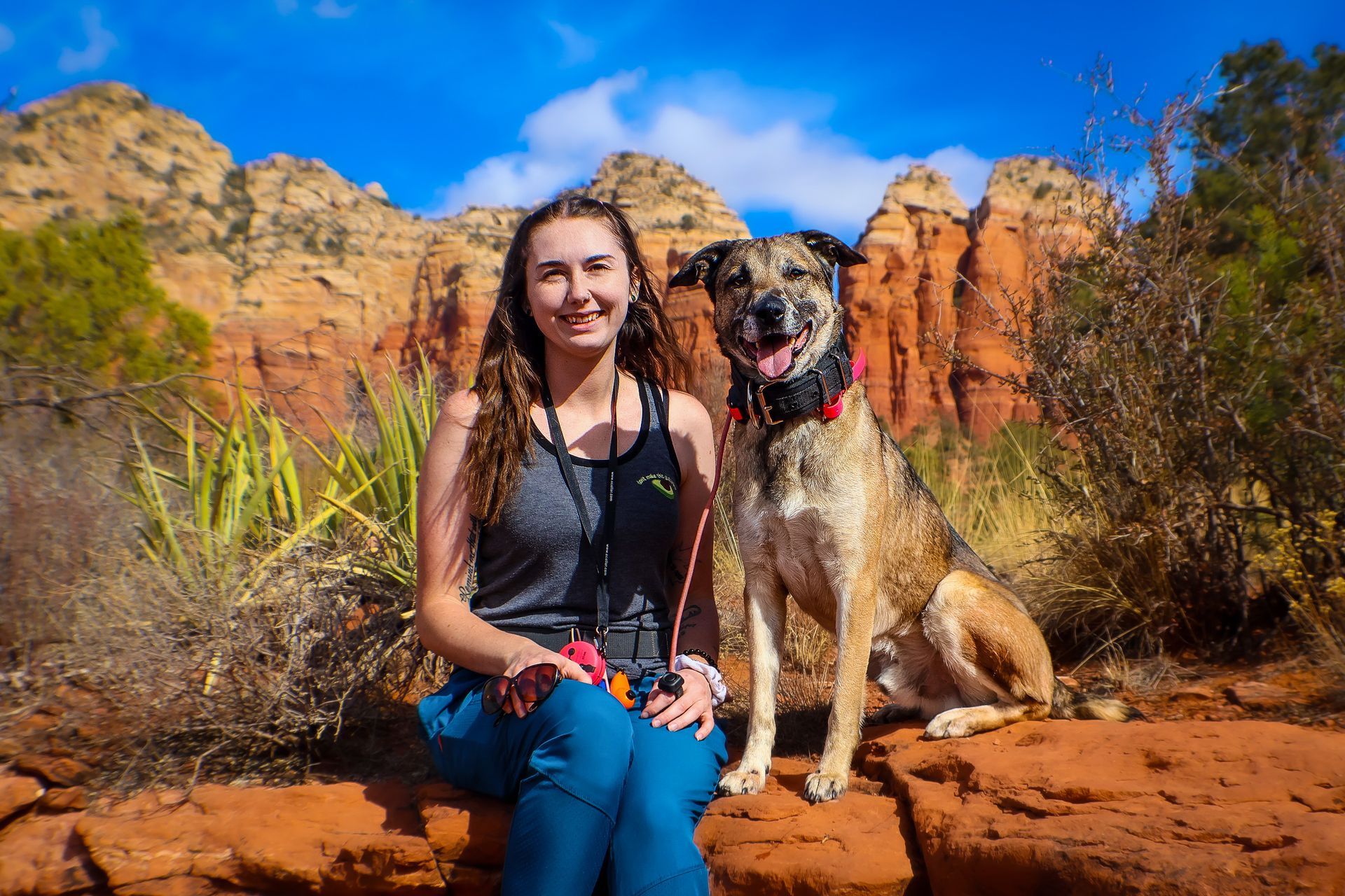 A woman is sitting on a rock next to a dog.