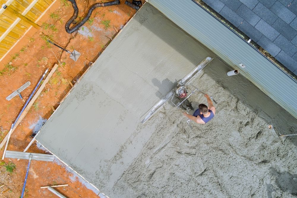 An aerial view of a man pouring concrete on a construction site.