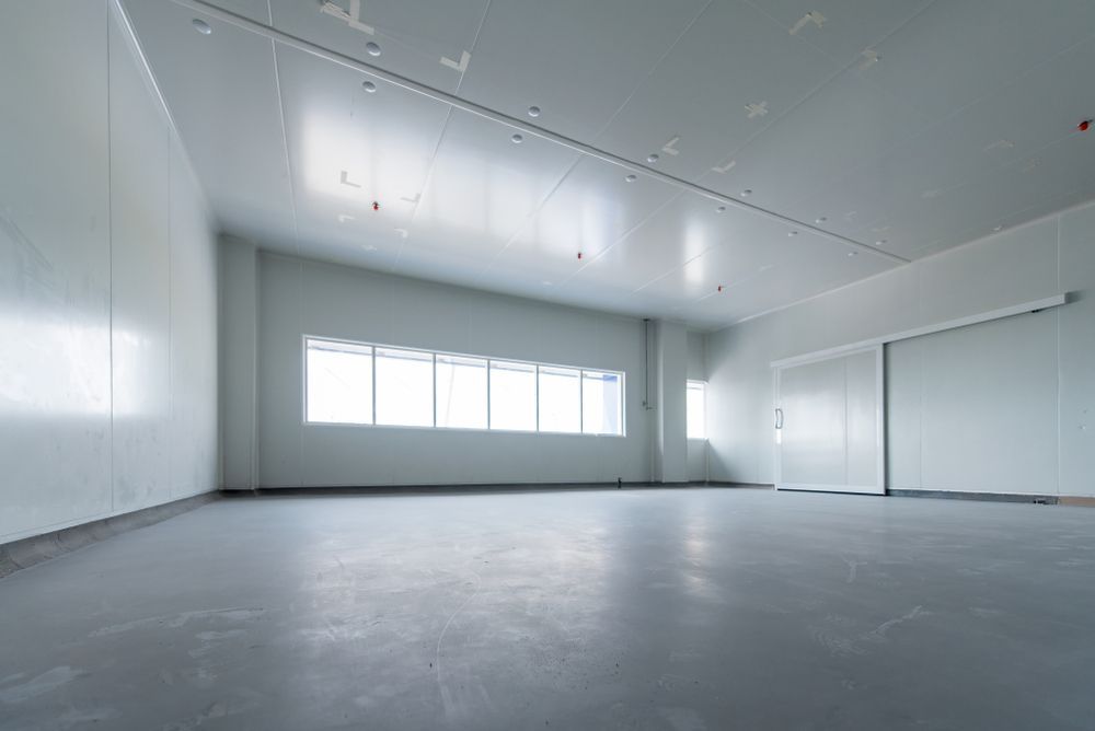 An empty garage with a lot of windows and a concrete floor.