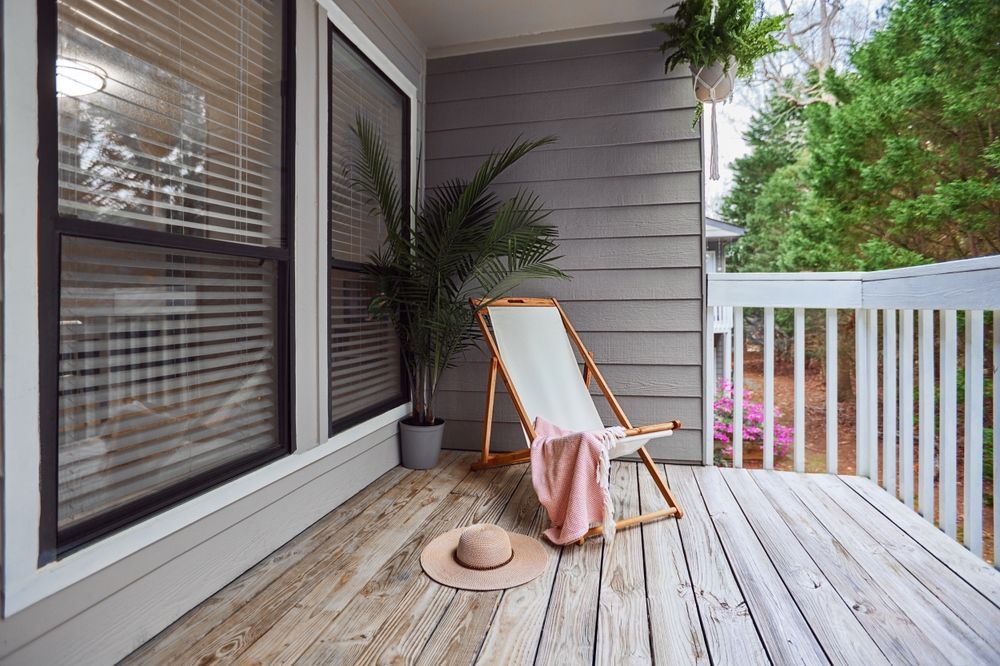 There is a deck with a chair and a hat on it.