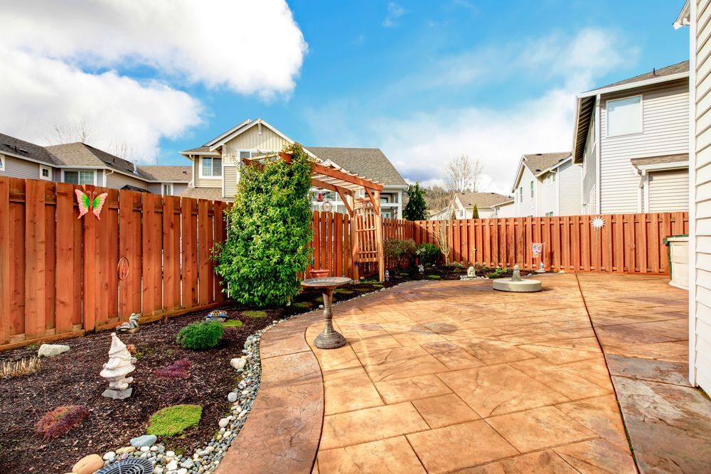 A backyard with a wooden fence and a patio.