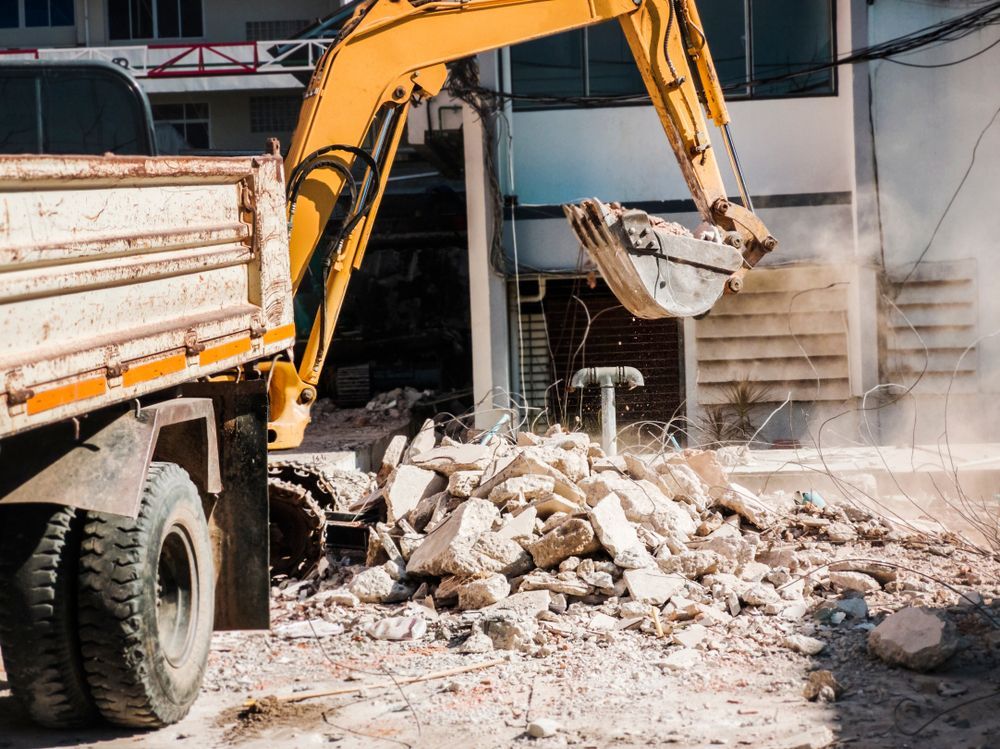 A yellow excavator is loading rocks into a dump truck.