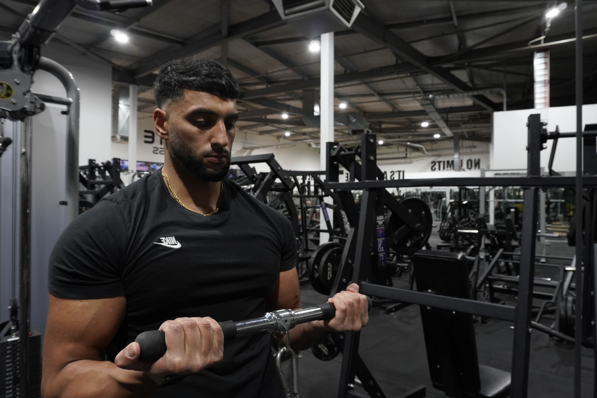 Manni kumar  is lifting a barbell in a gym.