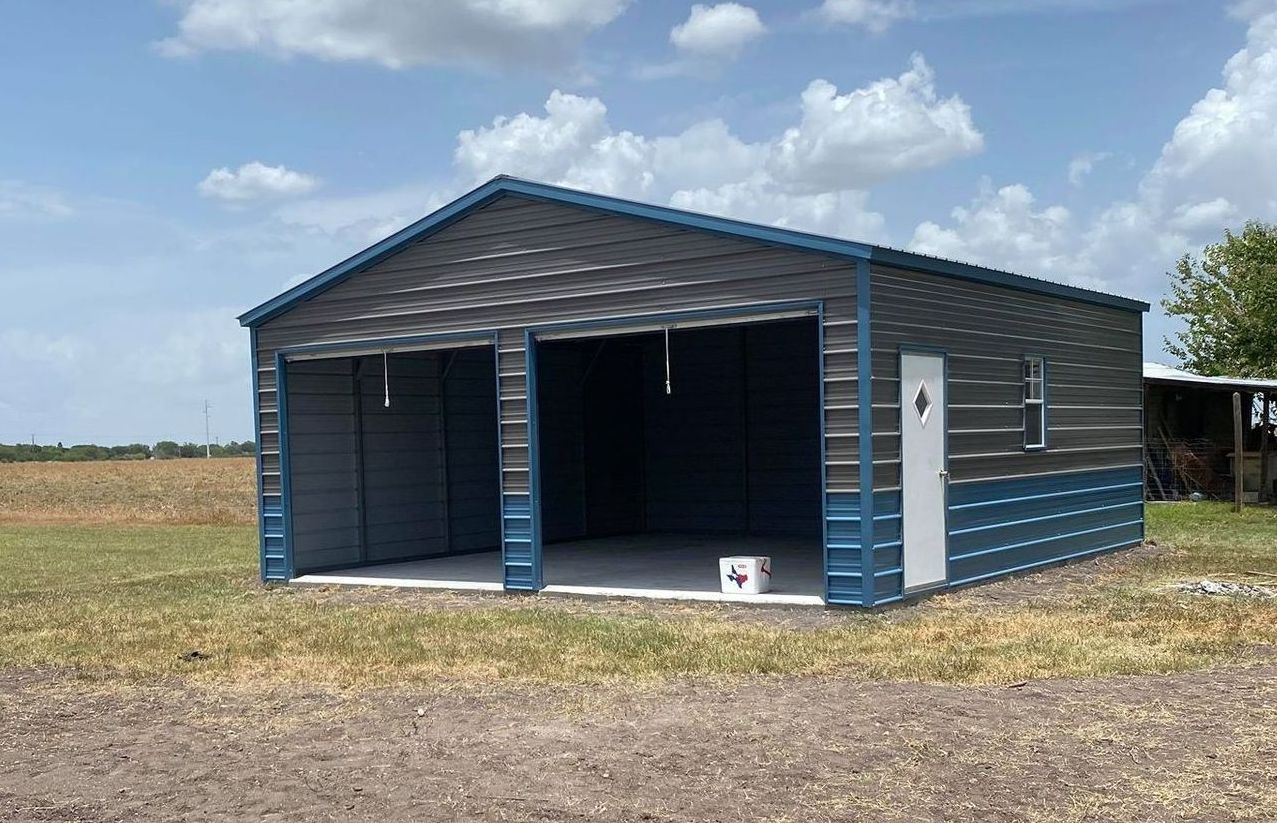 20 foot by 25 foot two car metal garage with two toned zinc grey and blue siding and blue trim with both garage bay doors rolled up