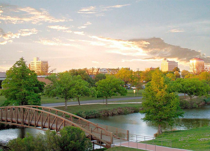 Sunset view of a park along the Concho River with downtown San Angelo in the background.