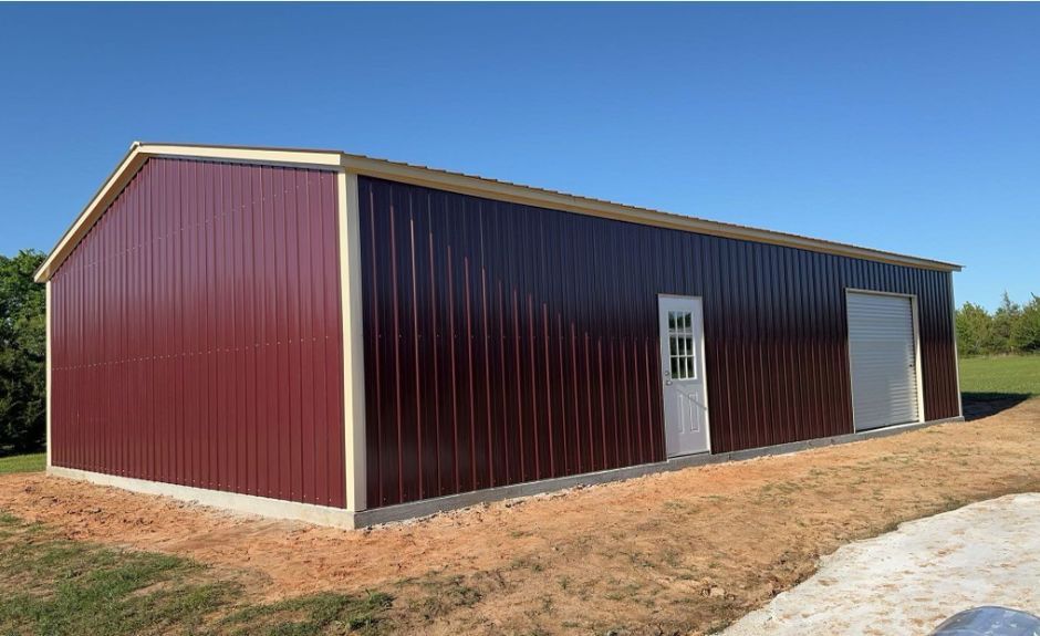 30'x60'x12' Vertical Panel Maroon Commercial Steel Building with Beige Trim. Building has one 8'x8' White Roll Up Door and one White Walk in Door.