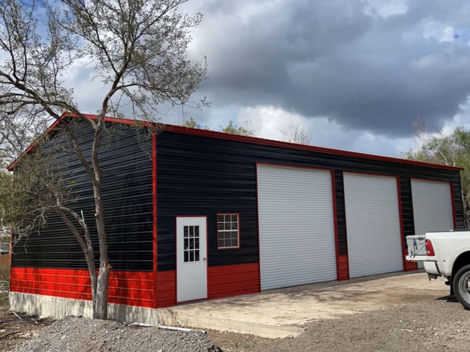 30'x50'x14' Blue and Red Commercial Metal Garage with three roll up doors, one walk in door, and one window.