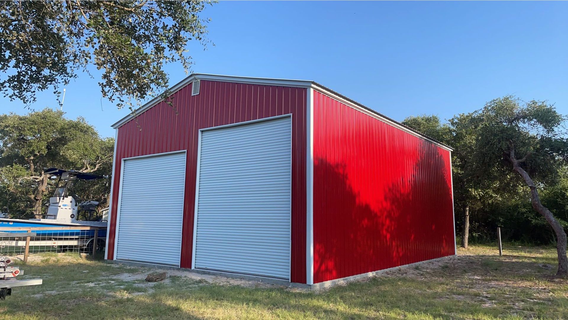 Red 24x40x14 RV Garage with white trim, white roll up doors, and an A frame horizontal roof.