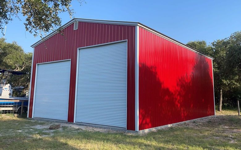 Enclosed RV and Truck Garage with red siding, white roll up doors and an A-frame roof.