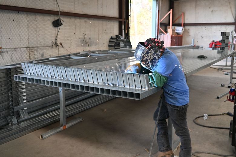 A worker welds a metal building frame together in the workshop at East Texas Carports in Longview, TX.