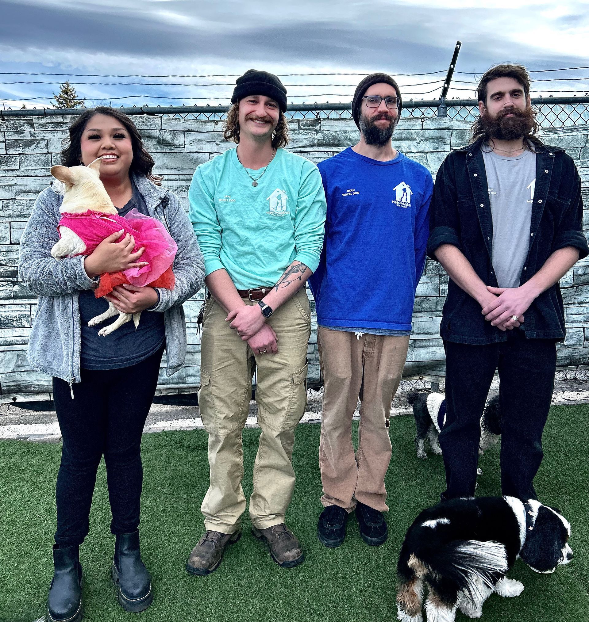 4 employees smiling with dog in outside play space