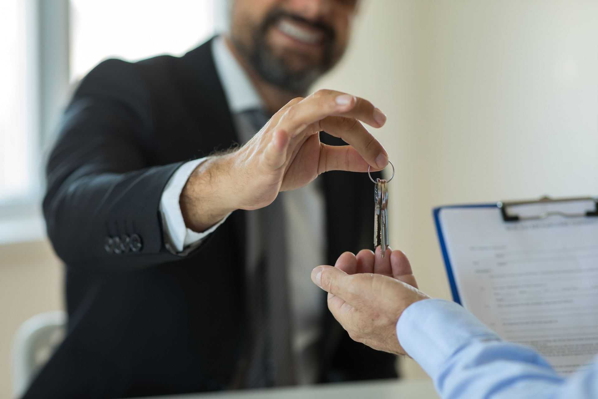 A man in a suit is handing a key to another man.